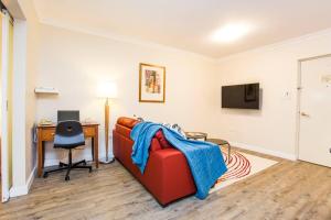 a living room with a red couch and a desk at Perth City Living 105 in Perth