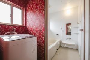 een badkamer met rode muren, een wastafel en een bad bij Bell-Rental Villa Engawa House in Fujikawaguchiko
