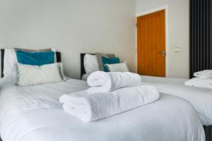 two white towels are stacked on a white bed at Long Eaton Modern 4bed House in Long Eaton