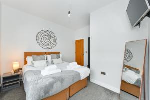 een slaapkamer met een groot bed en een spiegel bij Long Eaton Modern 4bed House in Long Eaton