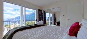 クイーンズタウンにあるBeautiful Lake Views Apartmentの大きなベッドと大きな窓のある寝室