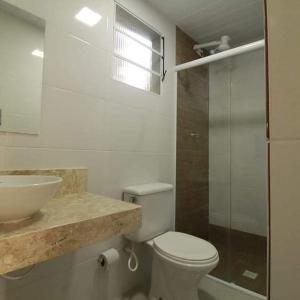 uma casa de banho com um WC branco e um lavatório. em Toca do Capitao em Boiçucanga