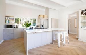 a white kitchen with white cabinets and white stools at Middedorp Manor in Stellenbosch