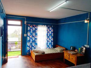 Schlafzimmer mit blauen Wänden, einem Bett und einem Fenster in der Unterkunft Well Spring Homestay in Kalimpong