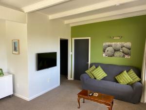 a living room with a gray couch and a green wall at Sounds Good - Waikawa Holiday Home and Berth in Picton