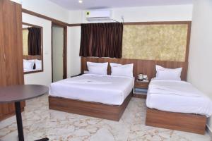 um quarto de hotel com duas camas e uma mesa em hotel fortune sky em Bangalore