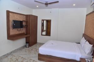 a bedroom with a bed and a tv on the wall at hotel fortune sky in Bangalore