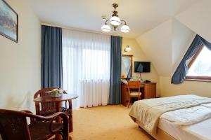 sypialnia z łóżkiem, stołem i biurkiem w obiekcie Hotel Burkaty w mieście Białka Tatrzanska