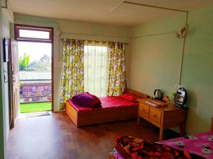 a bedroom with a bed and a desk and a window at Well Spring Homestay in Kalimpong