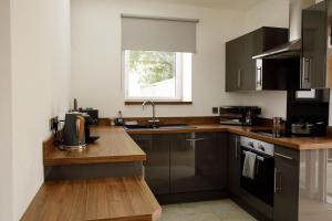 a kitchen with brown cabinets and a sink and a window at House of Juniper - Luxury Accessible Apartment in Broadford