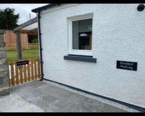 a white building with a window and a sign on it at House of Juniper - Luxury Accessible Apartment in Broadford