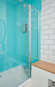 a blue bathroom with a shower and a tub at The Caledonian Hotel in Leven-Fife