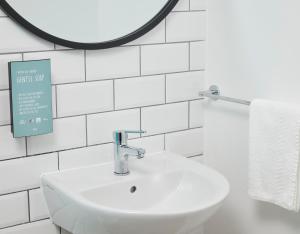 Baño blanco con lavabo y espejo en The Caledonian Hotel, en Leven