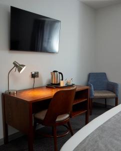 einen Schreibtisch mit einer Lampe und einem Stuhl in einem Zimmer in der Unterkunft The Caledonian Hotel in Leven-Fife