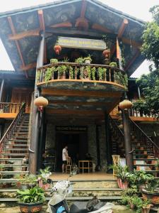 a person sitting in front of a building with a balcony at Khuổi Ky Eco Homestay in Cao Bằng