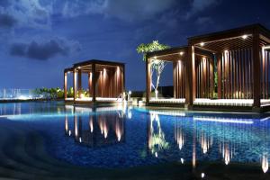 a pool at night with two pavilion at The Luxton Cirebon Hotel and Convention in Cirebon