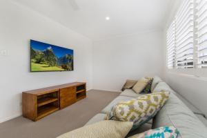 a living room with a couch and a tv on the wall at Key Ct 10 in Noosa Heads