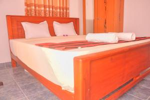 a large wooden bed with white sheets and white pillows at Himashi Sea View Homestay in Gandara East