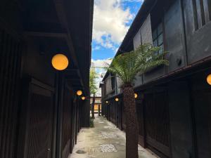 京都的住宿－Rinn Shiki Juraku，两座建筑之间的小巷里棕榈树