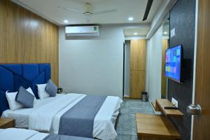 a hotel room with two beds and a flat screen tv at HOTEL SURY VILLA in Ahmedabad