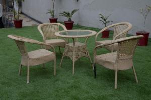 three wicker chairs and a table and chairs on grass at Hyphen Premier-Business Hotel in Meerut