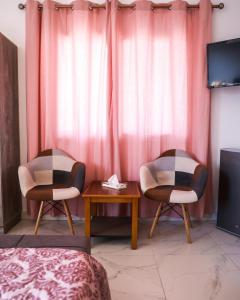 2 Stühle und ein Tisch in einem Zimmer mit rosa Vorhängen in der Unterkunft Reef Zefta Hotel in Zefta
