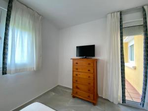 TV en un tocador en una habitación con ventana en Entre hoyos y la playa Grupo AC Gestion, en Novo Sancti Petri