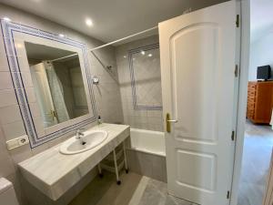 a bathroom with a sink and a mirror and a tub at Entre hoyos y la playa Grupo AC Gestion in Novo Sancti Petri