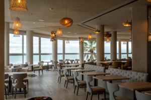 restauracja ze stołami i krzesłami oraz widokiem na ocean w obiekcie Cádiz Bahía by QHotels w Kadyksie