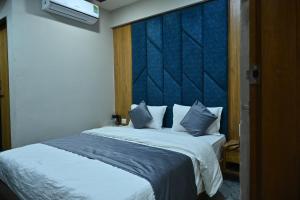 a bedroom with a large bed with a blue headboard at HOTEL SURY VILLA in Ahmedabad