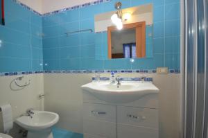 a blue tiled bathroom with a sink and a toilet at Appartamenti da Clarissa in Macari