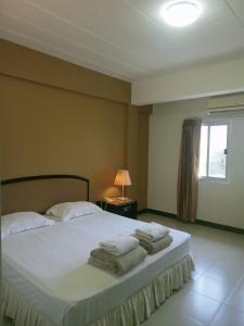 1 dormitorio con 1 cama con toallas en Tinidee Inn Ranong, en Ranong