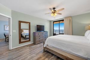 een slaapkamer met een bed, een televisie en een spiegel bij Phoenix X 603 in Orange Beach
