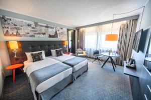 Cette chambre comprend un grand lit et une table. dans l'établissement Holiday Inn Lübeck, an IHG Hotel, à Lübeck