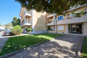 un immeuble d'appartements avec une pelouse devant lui dans l'établissement Apartamento junto NOVA&PRAIA Carcavelos II, à Carcavelos