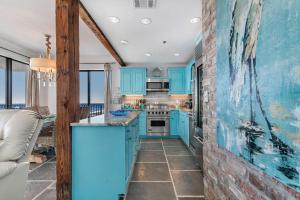 a kitchen with blue cabinets and a brick wall at Phoenix Vll 1401 in Orange Beach