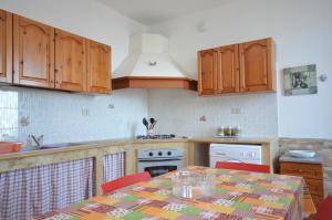 a kitchen with wooden cabinets and a table with chairs at Appartamenti da Clarissa in Macari