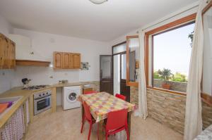 a kitchen with a table with red chairs and a window at Appartamenti da Clarissa in Macari