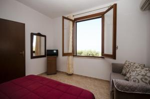 Appartamenti da Clarissa في ماكاري: غرفة نوم بسرير ونافذة واريكة