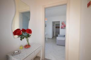 a vase of red roses on a counter with a mirror at Appartamenti da Clarissa in Macari