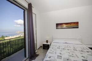 a bedroom with a bed and a large window at Appartamenti da Clarissa in Macari