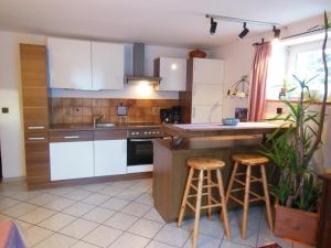 a kitchen with white cabinets and bar stools at Appartement im Souterrain mit Terrasse in Bischofswiesen