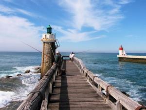 ein Pier mit zwei Leuten, die auf einem Leuchtturm fischen in der Unterkunft Charmant T3 de standing à Capbreton, jardin, 3 chambres, terrasse couverte, proche port et plages - FR-1-239-484 in Capbreton