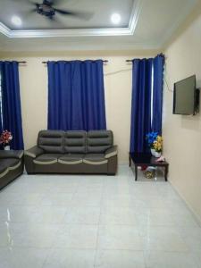salon z kanapą i niebieskimi zasłonami w obiekcie Zarina's Budget Homestay w mieście Tumpat
