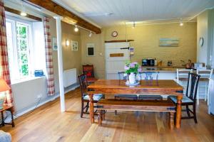 a dining room with a wooden table and a kitchen at Admiral's Cottage in Bridport
