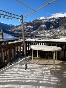 un banco en un balcón con una montaña cubierta de nieve en La maison de Linanna, en Aymavilles