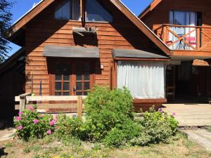 a wooden house with a porch and flowers in front of it at Cabaña Ruca Quimey in Villarrica