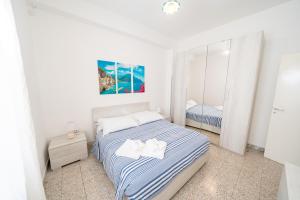 a white bedroom with a bed and a mirror at DACHI HOLIDAY HOUSE in Amalfi