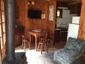een keuken met een tafel, een bank en een fornuis bij Cabaña Ruca Quimey in Villarrica