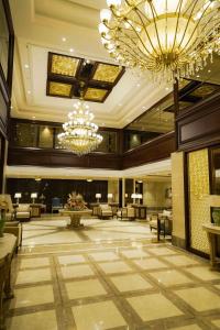 un gran vestíbulo con lámparas de araña, mesas y sillas en The Grand Nirvana Hotel, en Bareilly